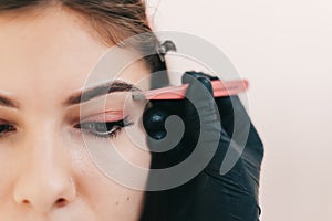 Eyebrow shaping procedure, make-up master uses tweezers to shape the eyebrows