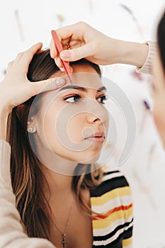 Eyebrow shaping procedure, make-up master uses tweezers to shape the eyebrows