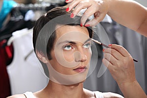 Eyebrows with makeup brush, model at mirror in dressing room