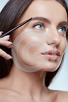 Eyebrows Makeup. Woman Shaping Brow With Cosmetic Brush. Beautiful Girl Close Up Portrait.