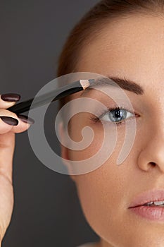 Eyebrows shaping. Beauty young woman with brow pencil.