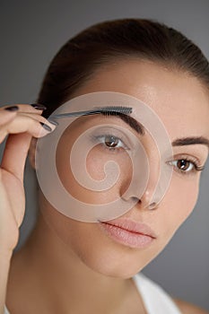 Eyebrows shaping. Portrait of beautiful girl with brow pencil. Close-up of young woman with professional makeup contouring brows w