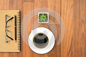 Eyeglasse and notepad with coffee cup on wood deck