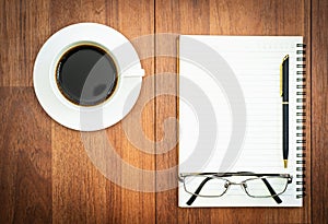 Eyeglasse and notepad with coffee cup on wood deck