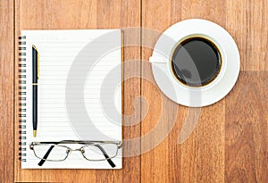 Eyeglasse and notepad with coffee cup on wood deck
