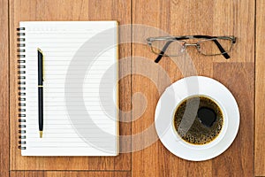 Eyeglasse and notepad with coffee cup on wood deck