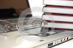 Eyeglasses and books on laptop