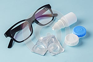 Eyeglasses and contact lenses with container on blue background