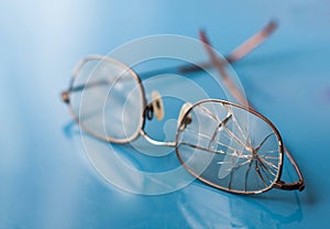 Eyeglasses with cracked lens on shiny blue background photo