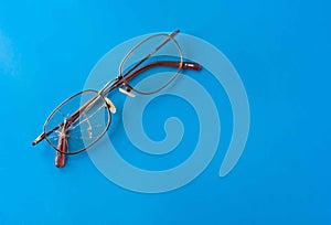 Eyeglasses with cracked lens on shiny blue background