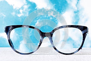 Eyeglasses Glasses with Bifocals and Black Blue Frame smudged agaist a blue and cloudy sky