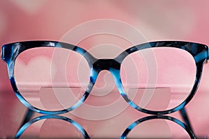 Eyeglasses Glasses with Bifocals and Black and blue Frame smudged view agaist a blurry pink  background with white hearts. Blurry