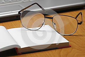 Eyeglasses,laptop and notebook.