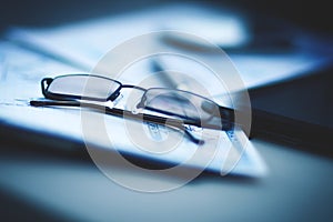 Eyeglasses lie on the documents and charts, next to the Tablet PC