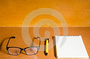 Eyeglasses, notebook and pen on wooden table