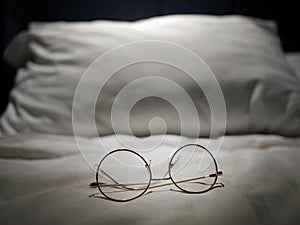 An eyeglasses optics on white linen bed, low light night time, shortsighted, nearsighted, farsighted, eyewear business products,