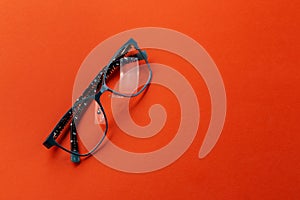 Eyeglasses on orange background, myopia or presbyopia.  Eyesight correction