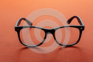 Eyeglasses on orange background, myopia or presbyopia.  Eyesight correction