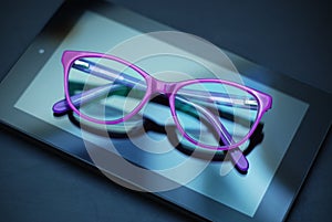 Eyeglasses over Tablet and Mobile Phone over Yellow Background with copy space. Education, technoogy, internet.