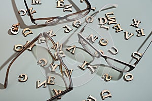 Eyeglasses on pastel green background with wooden letters. Vision test,optical store concept