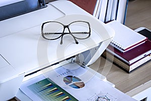 Eyeglasses on printer with books