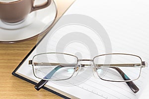 Eyeglasses put on note pad open blank page