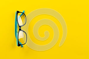 Eyeglasses on yellow background, myopia or presbyopia. Eyesight correction. Fashion accessories. Space for text