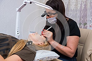 Eyelash extension master long eyelashes beautiful girl in a beauty salon. Eyelash extension procedure.