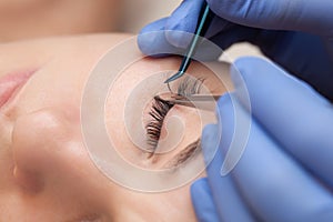 Eyelash extension procedure close up. Beautiful woman with long eyelashes in a beauty salon. Makeup concept