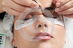 Eyelash extension procedure close up. Beautiful Woman with long lashes in a beauty salon