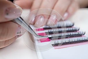 Eyelash Extension Procedure. Close-up of a master at work artificial eyelash extensions material. Hands of the master