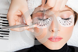 Eyelash extension procedure. Master tweezers fake long lashes beautiful female eyes