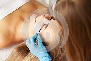 Eyelash extension procedure, professional stylist lengthening female lashes.
