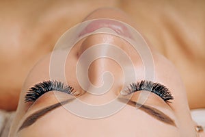 Eyelash Extension Procedure. Woman Eye with Long Eyelashes. Close up, selective focus.