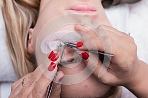 Eyelash Extension Procedure. Woman Eye with Long false Eyelashes. Closeup macro shot of fashion eyes in beauty salon