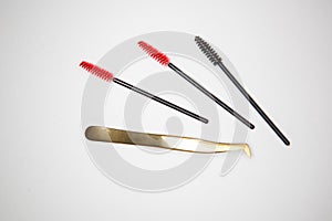 Eyelash extension tools, golden tweezers and red-black brushes