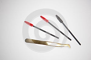 Eyelash extension tools, golden tweezers and red-black brushes