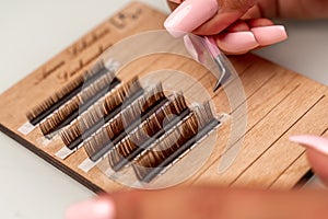 Eyelash extensions, lashmaker tools. Artificial eyelashes on a white tablet and pink silicone brush comb, close up.