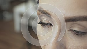 Eyelash extensions, makeup artist sticks eyelash bunches, bright glamorous party look. makeup in a beauty salon
