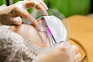 Eyelash lamination procedure close up. Beautiful woman with long eyelashes in a beauty salon in medicine mask