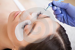 Eyelashes extensions. Fake Eyelashes. Eyelash Extension Procedure. Professional stylist lengthening female lashes
