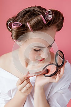 Eyeliner eye makeup beauty care woman. Girl putting eye pencil color on eyes looking in a pocket mirror smiling happy on pink