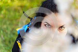 Eyes of attractive young woman through cherry blossom branch in spring in park