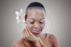 Eyes closed, flower and black woman with cosmetics, glow and wellness isolated on grey studio background. African person
