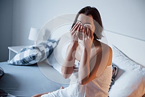 On the eyes. Time for a make up. Woman sits on the bed and use cosmetics to clean her skin