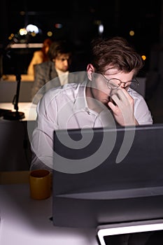 eyes of young male office worker hurt from overexertion, working on computer