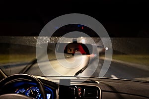 Eyes of young man taxi driver are reflected in rearview mirror during night trip around city