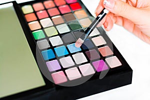 Eyeshadow palette closeup with a woman hand