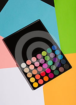 Eyeshadow palette laying on a colorful background.