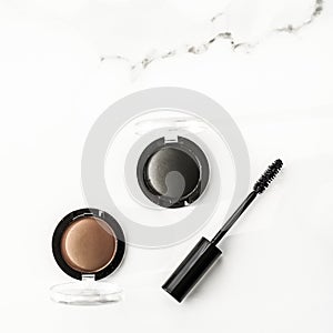 Eyeshadows, black liner and mascara on marble background, eye shadows cosmetics as glamour make-up products for luxury beauty